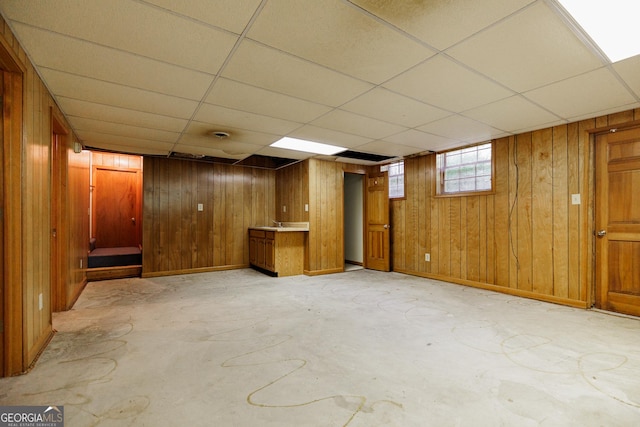 basement featuring a drop ceiling and wooden walls