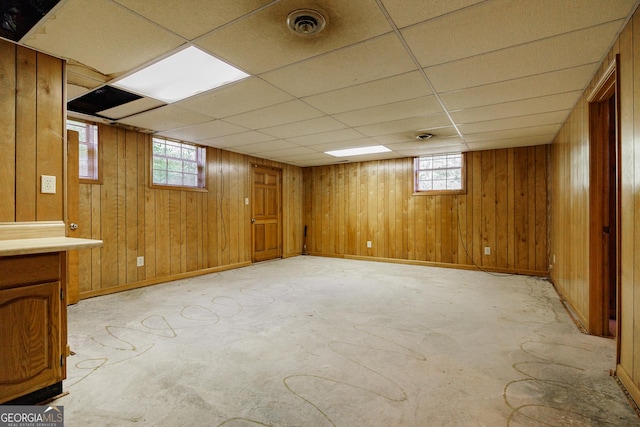 basement with a paneled ceiling and wooden walls