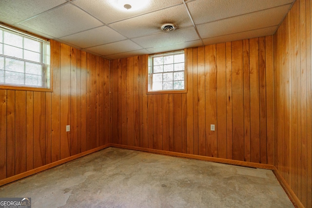 basement featuring wood walls and a drop ceiling