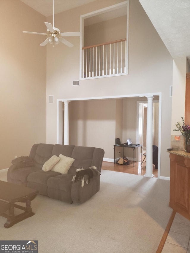 living room with decorative columns, ceiling fan, high vaulted ceiling, and light tile patterned flooring