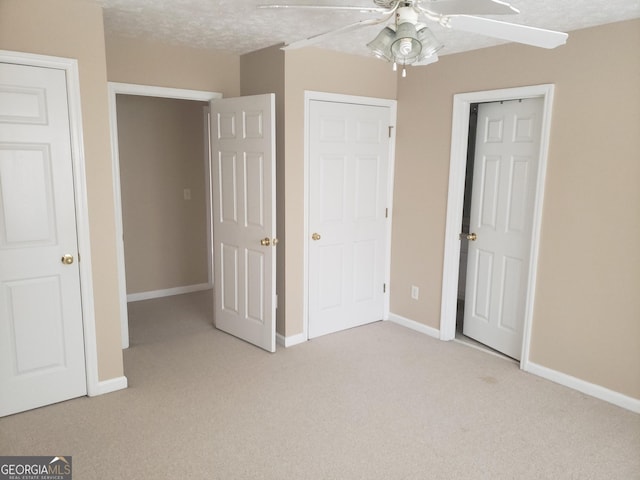 unfurnished bedroom featuring light carpet, a textured ceiling, and ceiling fan