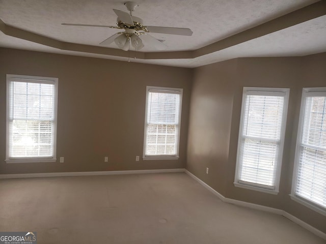 unfurnished room with ceiling fan and a tray ceiling