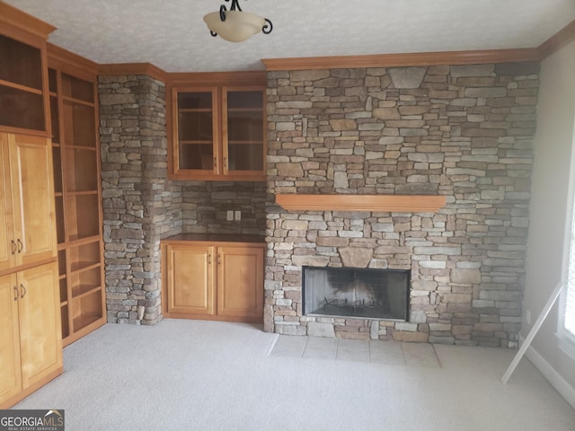 unfurnished living room featuring a stone fireplace, light colored carpet, and a textured ceiling