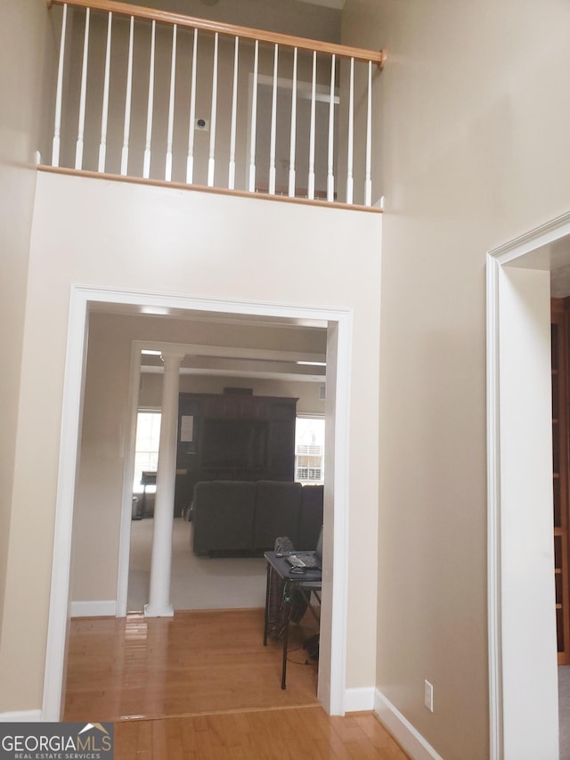 hallway with hardwood / wood-style flooring, ornate columns, and plenty of natural light