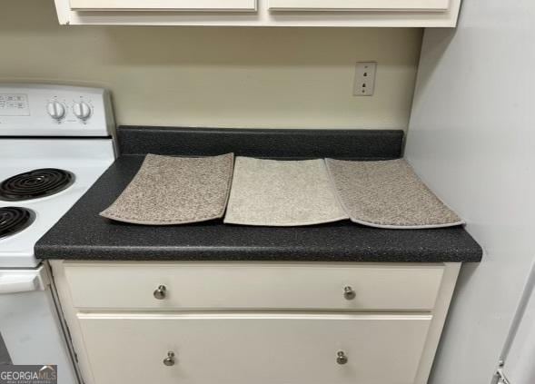 details featuring white electric range oven and white cabinetry