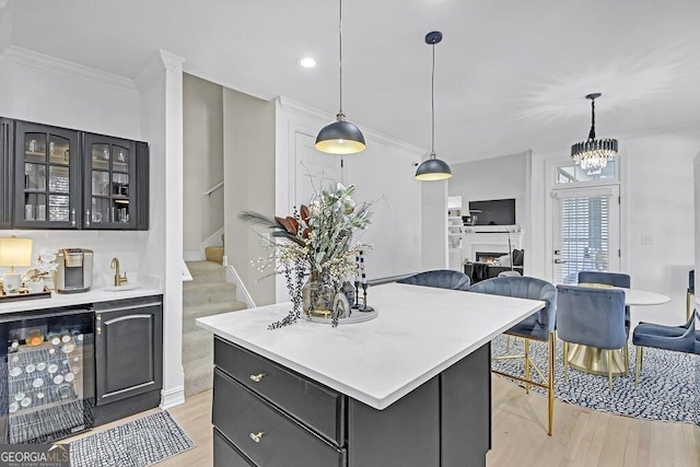 kitchen with wine cooler, a kitchen island, decorative light fixtures, and light wood-type flooring