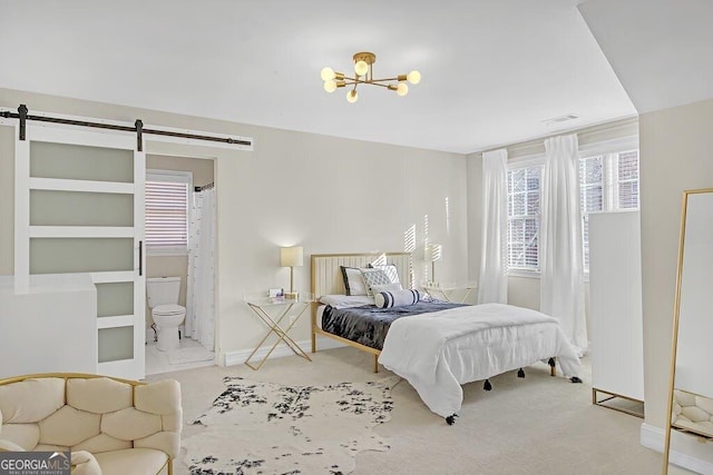 bedroom featuring carpet flooring, ensuite bath, a notable chandelier, and a barn door