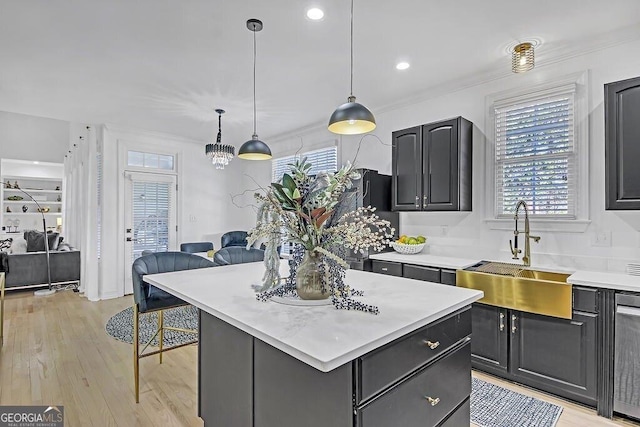 kitchen featuring sink, a center island, light hardwood / wood-style flooring, crown molding, and pendant lighting