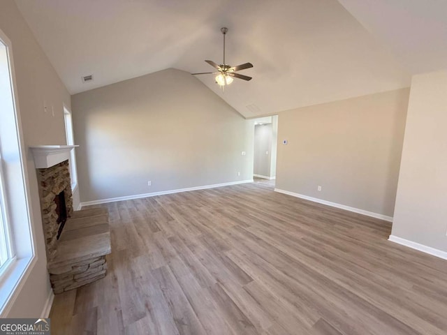 unfurnished living room with a fireplace, light hardwood / wood-style floors, vaulted ceiling, and ceiling fan