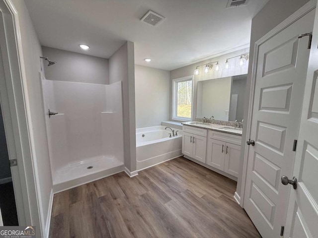 bathroom featuring plus walk in shower, wood-type flooring, and vanity