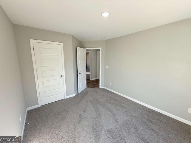 unfurnished bedroom featuring a closet and dark carpet