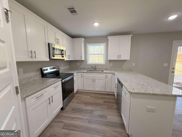 kitchen featuring white cabinetry, sink, stainless steel appliances, light stone counters, and light hardwood / wood-style floors