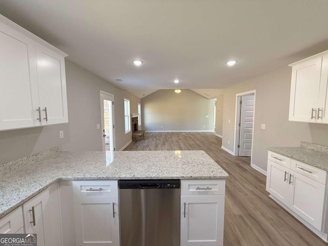 kitchen featuring dishwasher, lofted ceiling, white cabinets, light wood-type flooring, and light stone countertops