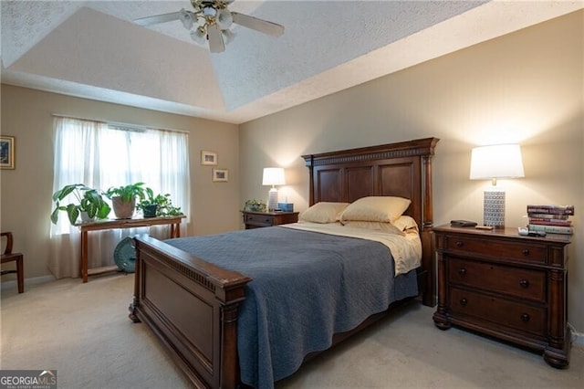 carpeted bedroom featuring a raised ceiling, ceiling fan, and a textured ceiling