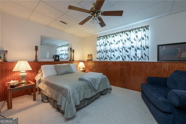 bedroom with carpet, wooden walls, and ceiling fan