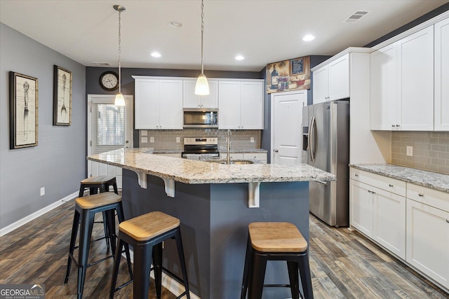 kitchen with white cabinetry, light stone countertops, sink, stainless steel appliances, and decorative light fixtures