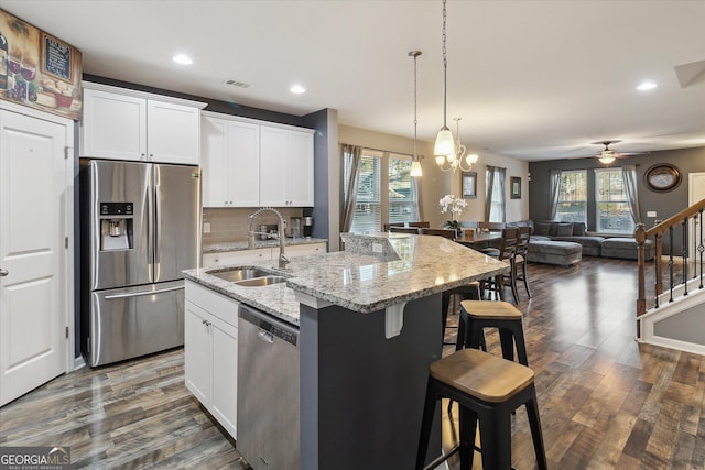 kitchen featuring white cabinetry, sink, stainless steel appliances, an island with sink, and ceiling fan with notable chandelier