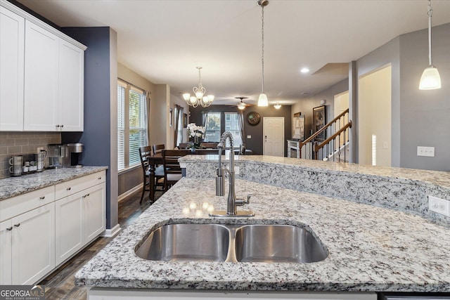 kitchen with ceiling fan with notable chandelier, tasteful backsplash, a center island with sink, and sink