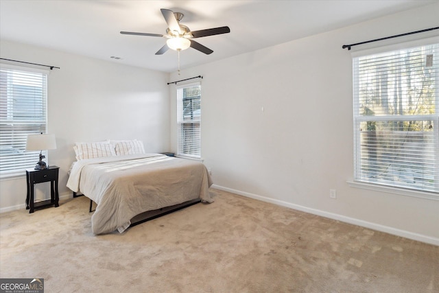 bedroom with multiple windows, ceiling fan, and light colored carpet