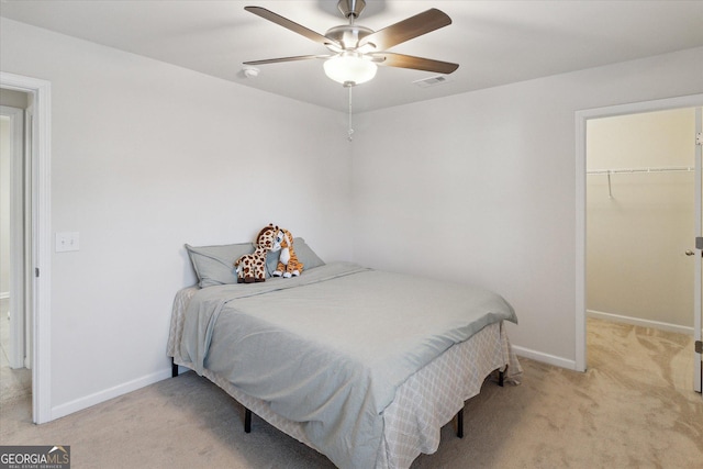 carpeted bedroom with ceiling fan, a closet, and a spacious closet