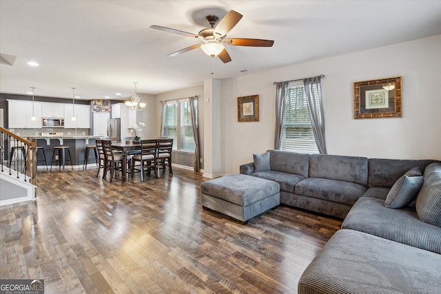 living room featuring dark hardwood / wood-style flooring and ceiling fan with notable chandelier