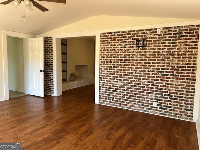 unfurnished room with dark hardwood / wood-style floors, ceiling fan, brick wall, and vaulted ceiling