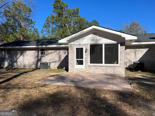 rear view of house with a sunroom, a yard, a patio, and central AC