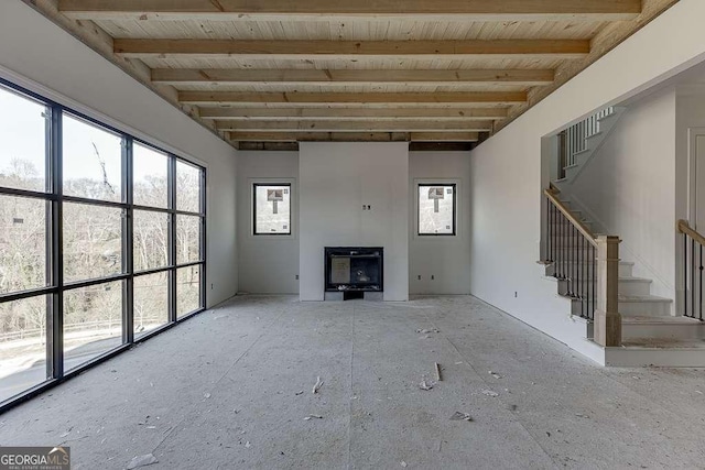 unfurnished living room with beamed ceiling, a wood stove, and wood ceiling