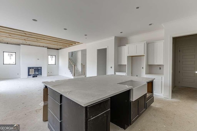 kitchen featuring a center island, light stone counters, white cabinetry, and sink