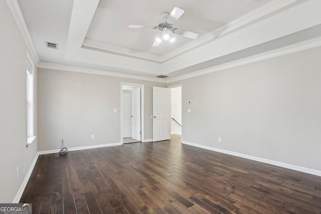 spare room with a raised ceiling, ceiling fan, dark wood-type flooring, and crown molding