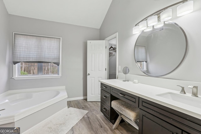 bathroom with a tub, vanity, lofted ceiling, and hardwood / wood-style flooring