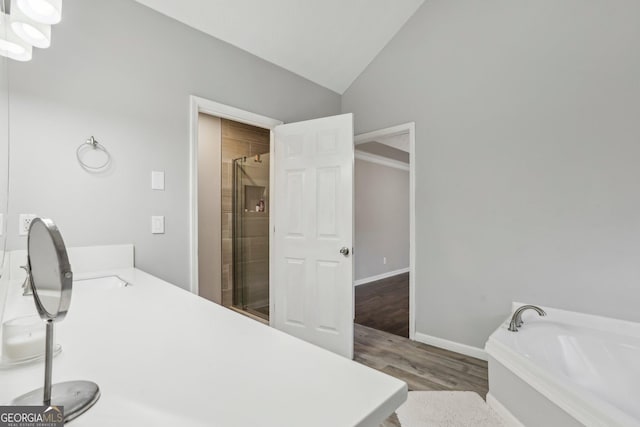 bathroom featuring vanity, plus walk in shower, vaulted ceiling, and hardwood / wood-style flooring