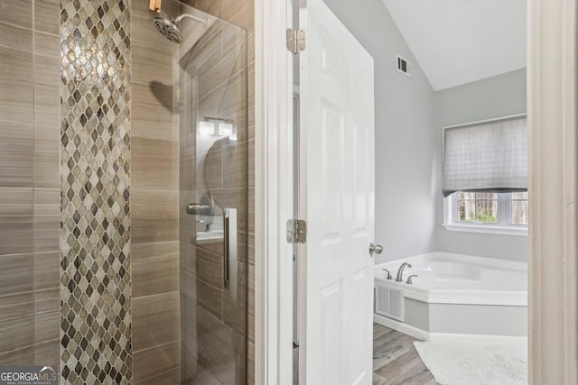 bathroom featuring wood-type flooring, shower with separate bathtub, and vaulted ceiling