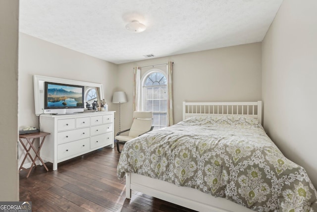 bedroom with a textured ceiling and dark hardwood / wood-style flooring