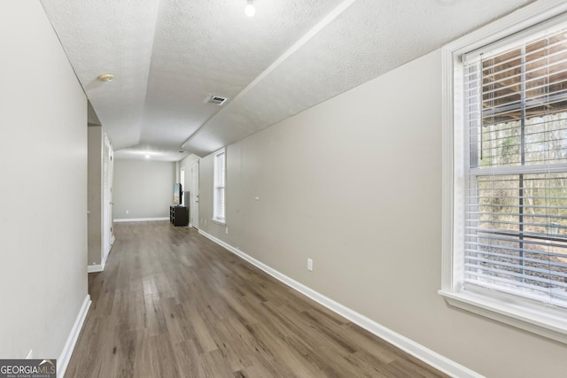 hall featuring hardwood / wood-style floors, a textured ceiling, and plenty of natural light