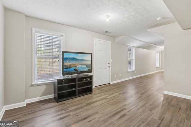 unfurnished living room with a textured ceiling and hardwood / wood-style flooring