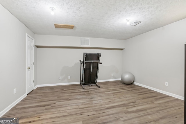 exercise area with hardwood / wood-style flooring and a textured ceiling