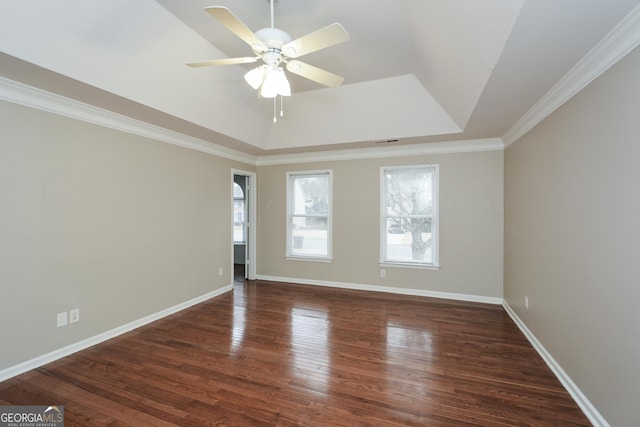 spare room featuring dark hardwood / wood-style floors, ceiling fan, ornamental molding, and a tray ceiling