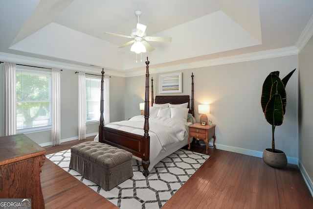 bedroom with hardwood / wood-style flooring, ceiling fan, a raised ceiling, and ornamental molding