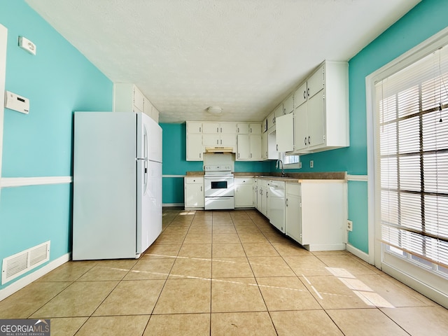 kitchen with white cabinets, white appliances, sink, and light tile patterned floors