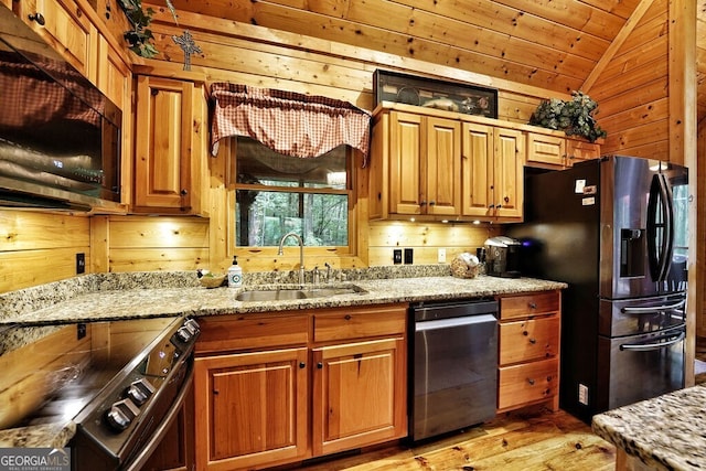 kitchen with light stone countertops, stainless steel fridge, sink, electric range, and wood walls