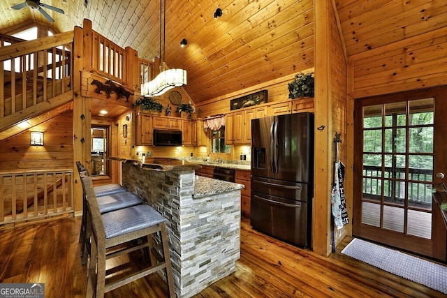 kitchen with pendant lighting, high vaulted ceiling, black appliances, and dark hardwood / wood-style floors