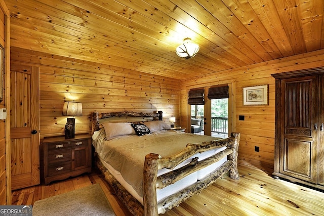 bedroom with light hardwood / wood-style floors, access to exterior, wooden ceiling, and wooden walls