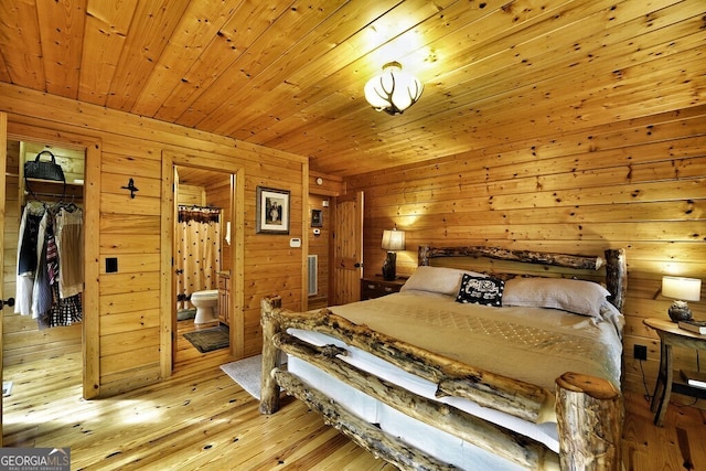 bedroom with ensuite bathroom, wooden walls, wooden ceiling, light hardwood / wood-style floors, and a closet