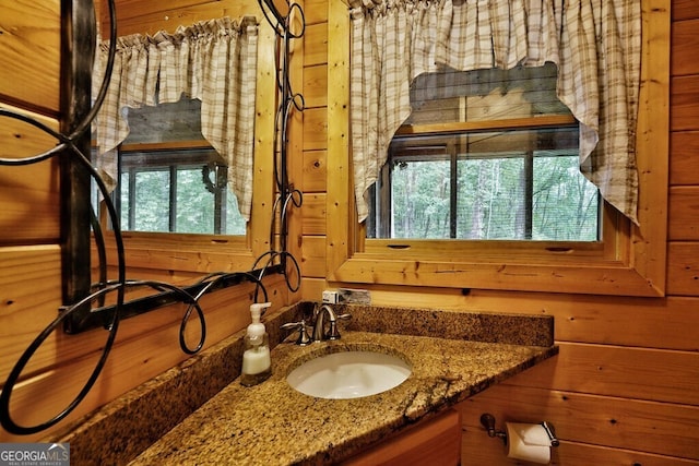 bathroom featuring plenty of natural light, wood walls, and vanity