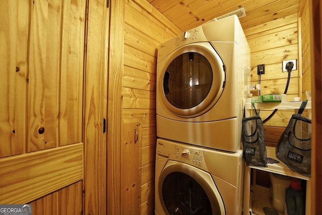 laundry area with wood walls, wooden ceiling, and stacked washer / drying machine