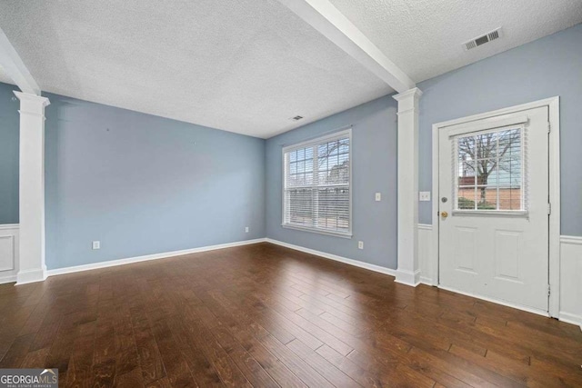 entryway featuring a textured ceiling, decorative columns, and dark wood-type flooring