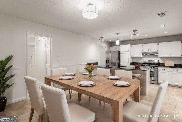 tiled dining area with sink and a textured ceiling