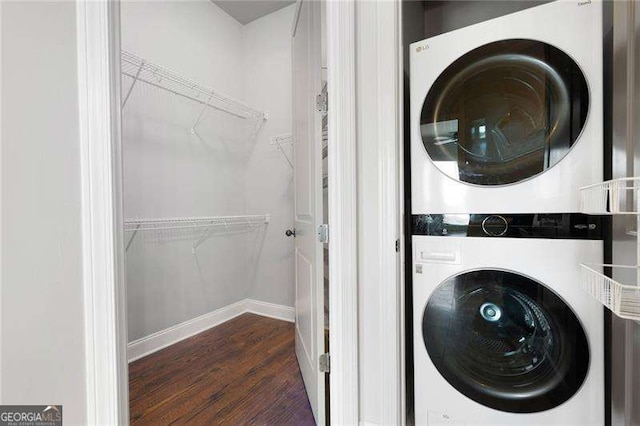 laundry room with dark hardwood / wood-style flooring and stacked washer and dryer