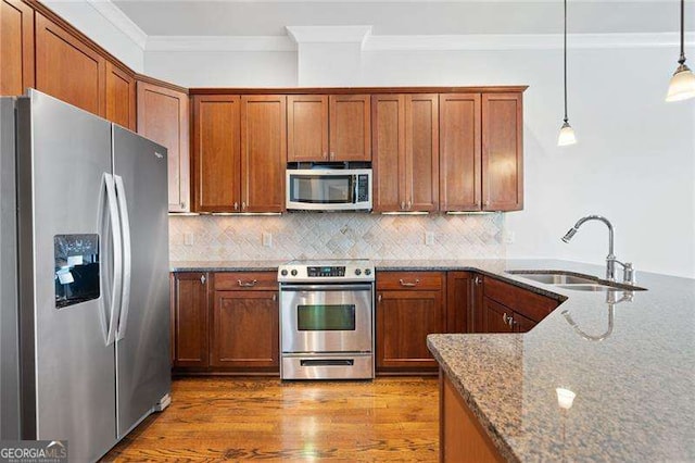 kitchen with sink, dark stone counters, pendant lighting, decorative backsplash, and appliances with stainless steel finishes